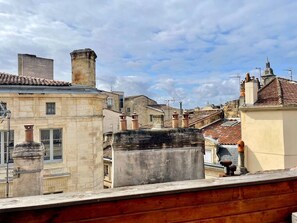 Paesaggio urbano con edifici storici, una struttura in pietra ben visibile e cielo sereno.