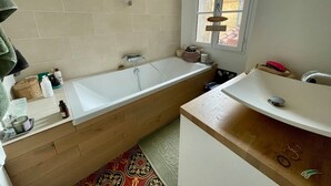 Een badkamer met een bad, een wastafel en een raam.