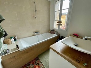 Un bagno con una vasca, un lavandino e una finestra.