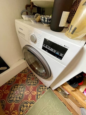 Una lavadora de carga frontal con panel de control, un lavamanos y un suelo estampado.