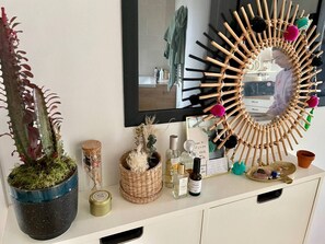 A bathroom vanity with a mirror, a potted plant, a decorative mirror frame, and various toiletries. - Rooftop dans hyper centre (Bordeaux)