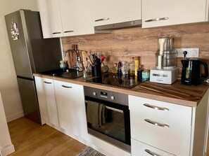 A modern kitchen with a stainless steel refrigerator, a built-in oven, and a coffee maker on the countertop.