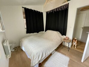 Un dormitorio con cama, una mesita, un perro y un radiador.