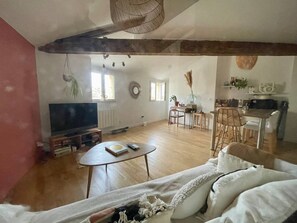A living room with a television, a dining area, and a kitchen.