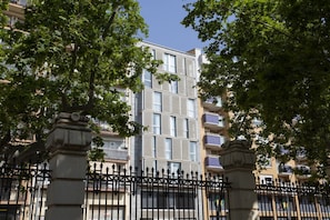 A multi-story building with balconies, surrounded by trees and a black wrought iron fence. - Studio with green views of Ribalta Park (Castellón)