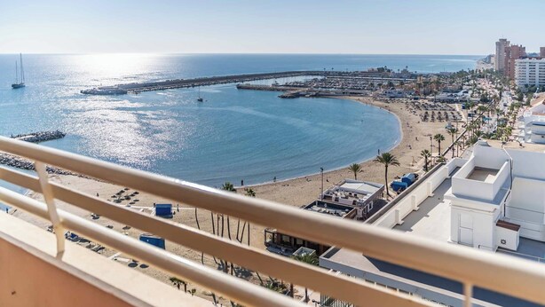 Ett hotell vid kusten med en balkong som vetter mot stranden, en brygga och havet.