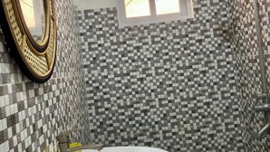 A bathroom with a checkered tile backsplash, a white sink, a mirror, and a shower.