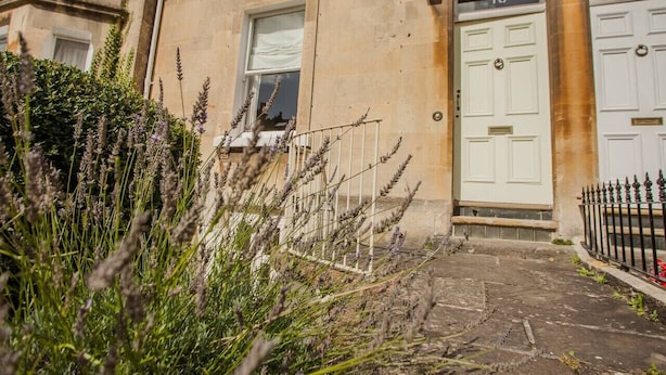 A building with a stone facade, a white door marked with the number 10, and a metal fence in front. - The Design Studio Apartment (Bath)