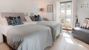 A modern bedroom with two beds, a sofa, and a large window. - The Design Studio Apartment (Bath)