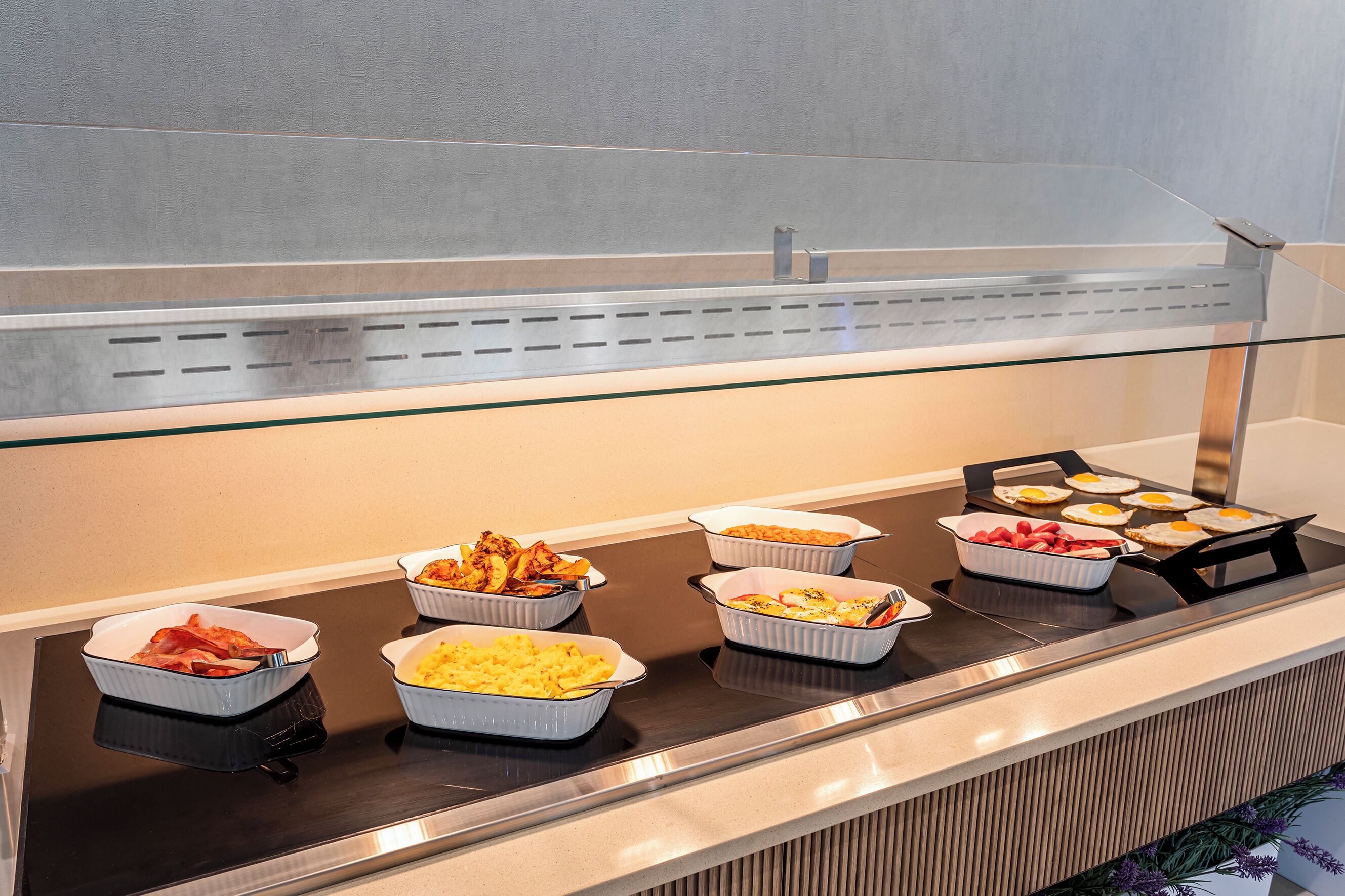 A buffet with various dishes including meats, eggs, and casseroles.