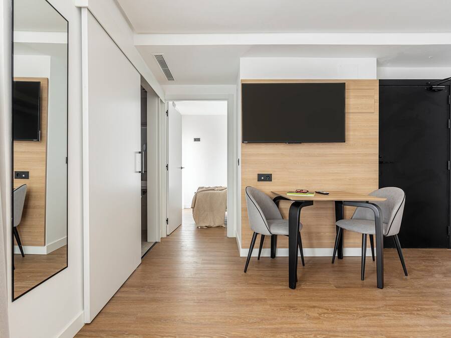 A modern dining area with a wooden table and two chairs, a blackboard on the wall, and a black door.
