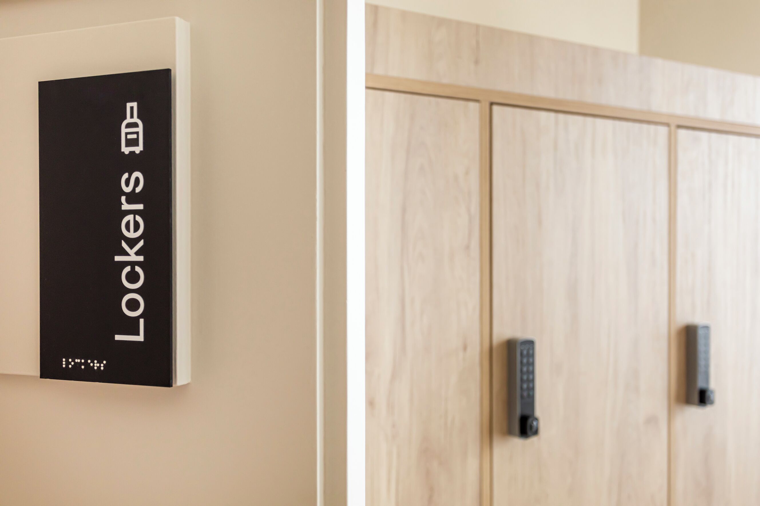A wall-mounted sign with the word 'Lockers' and a symbol of a key, indicating a locker area.