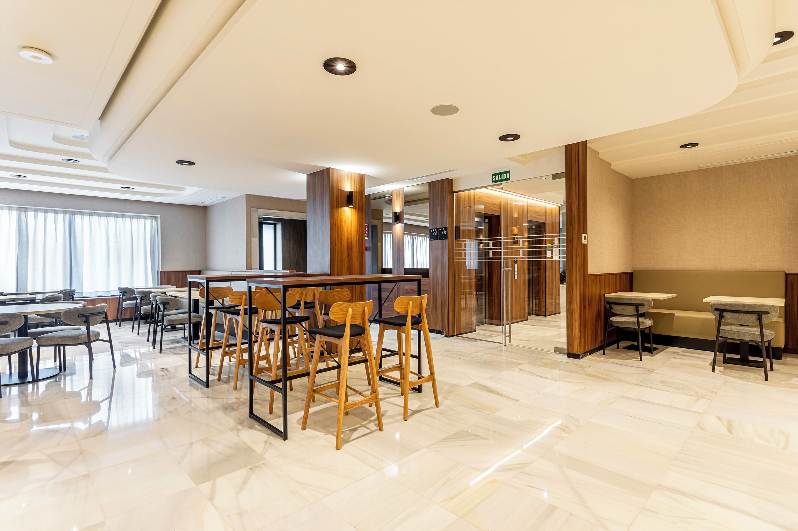 Un moderno vestíbulo de hotel con zona de bar, asientos y mostrador de recepción.
