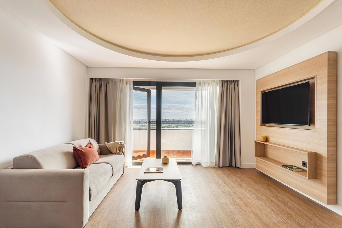 A modern living room with a sofa, coffee table, and TV mounted on a wooden wall.
