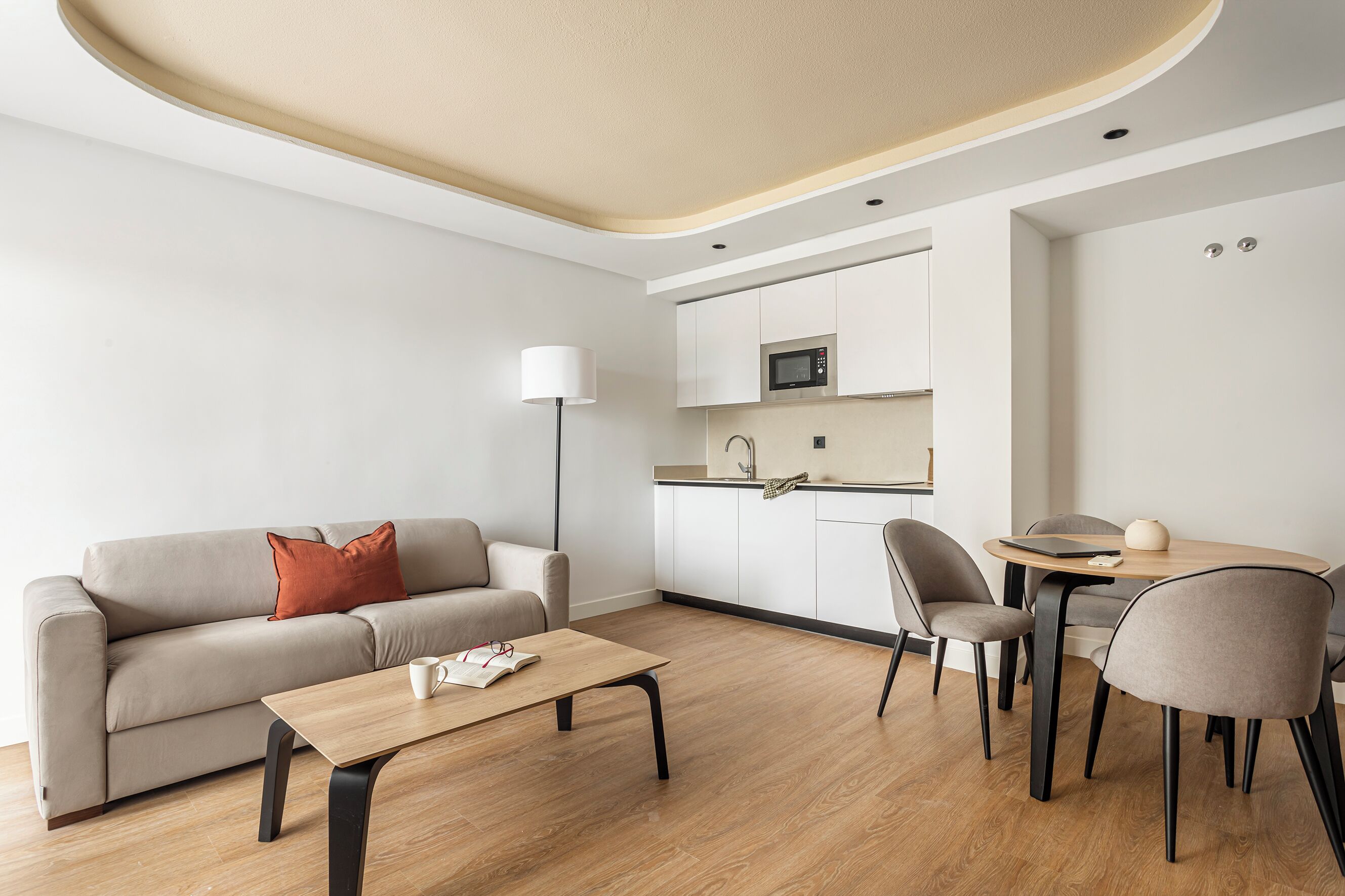A modern living room with a sofa, coffee table, and dining area with chairs.