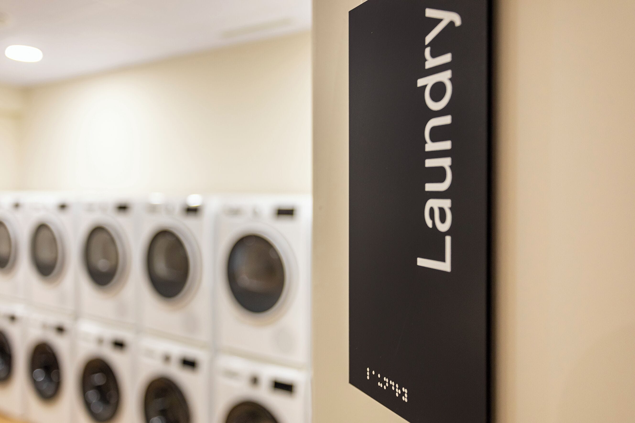 A laundry area with multiple washing machines and a sign indicating the location.