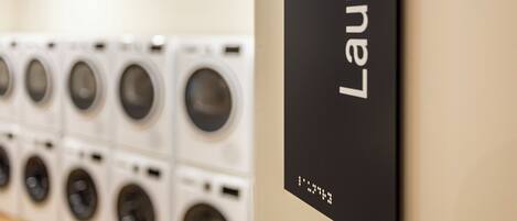 A laundry area with multiple washing machines and a sign indicating the location.