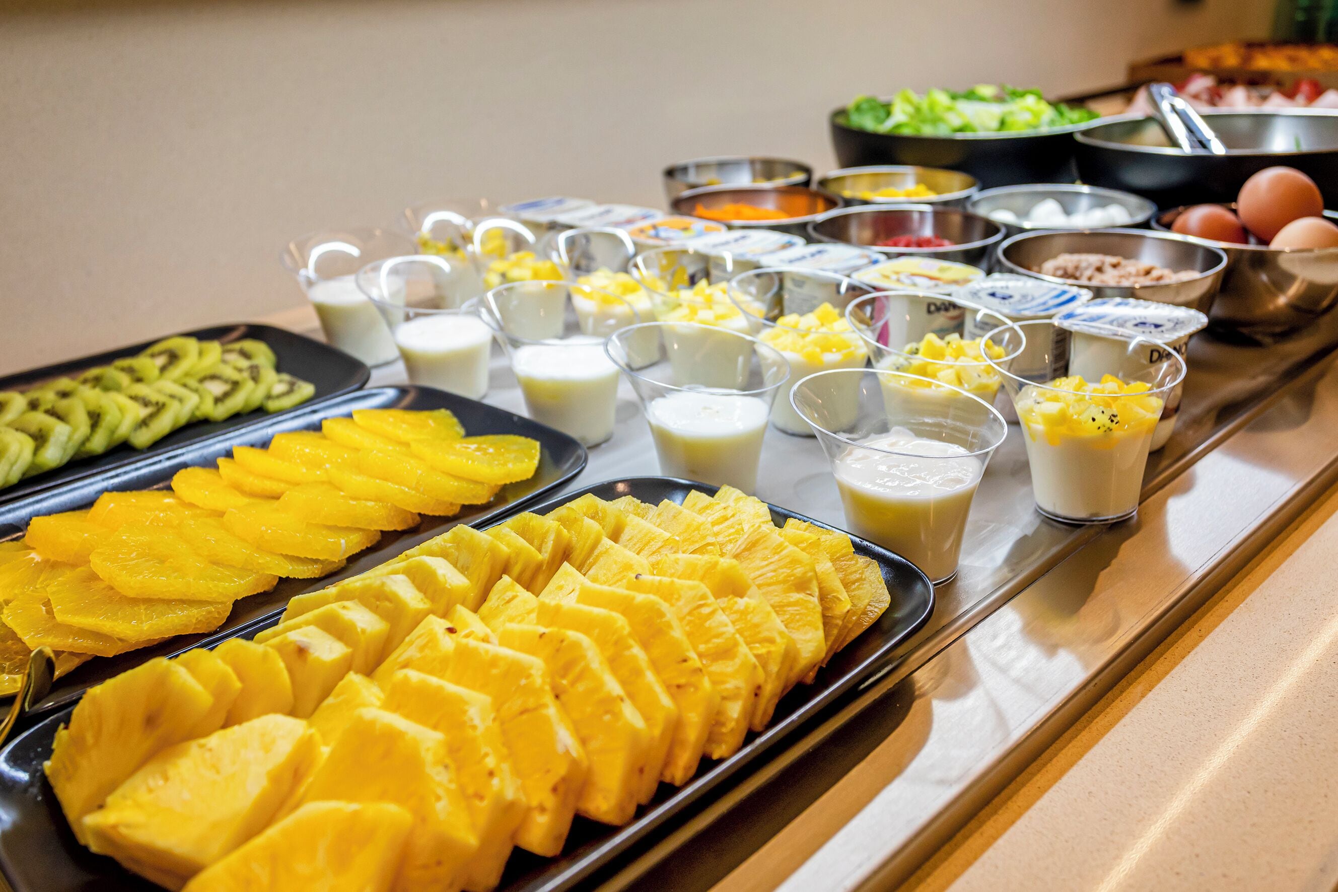 A buffet with various food items including sliced pineapple, milk, and other beverages.