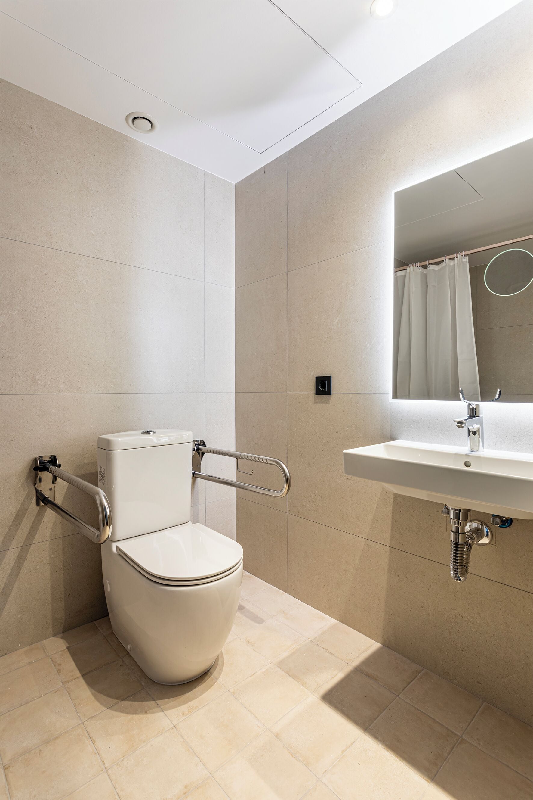 Un baño moderno con inodoro, lavamanos y espejo.