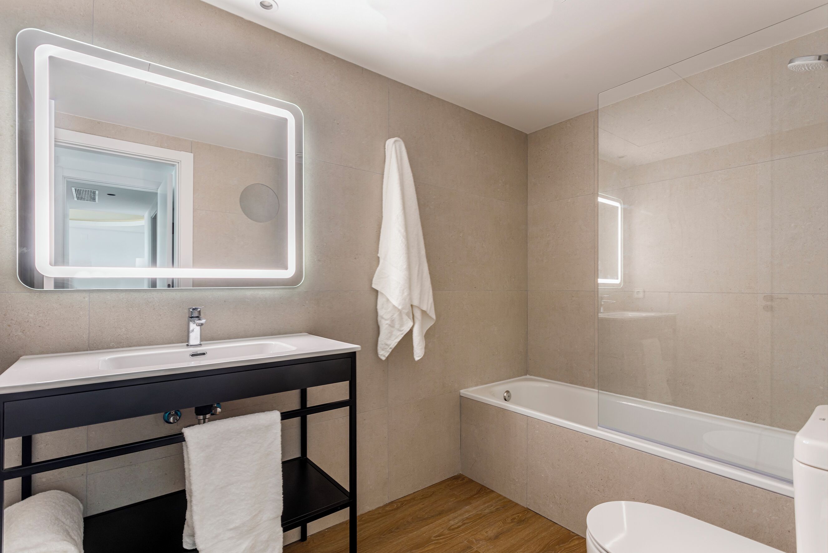 Une salle de bain moderne équipée d’un lavabo, d’un miroir, d’un porte-serviettes et d’une baignoire.