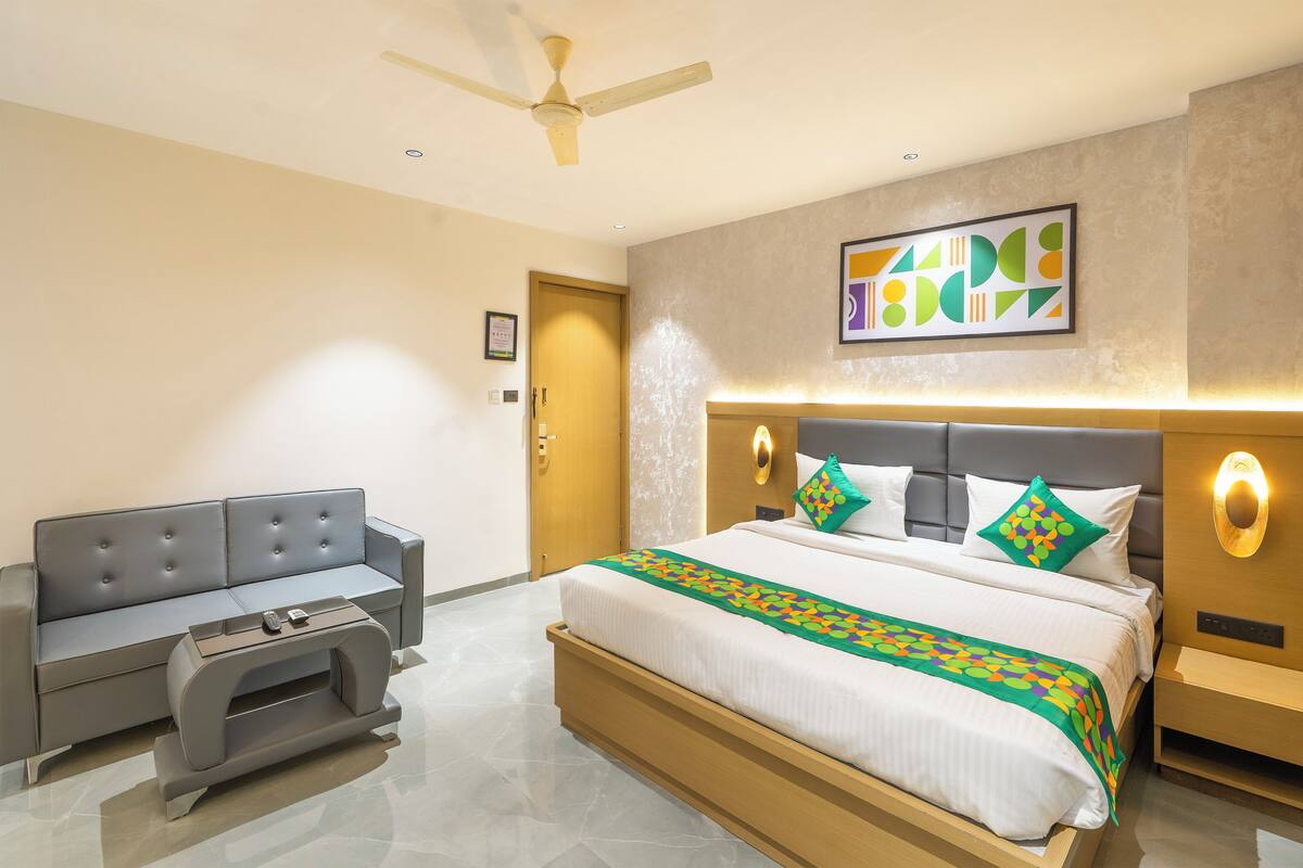 A modern hotel room with a bed, a sofa, and a bedside table.