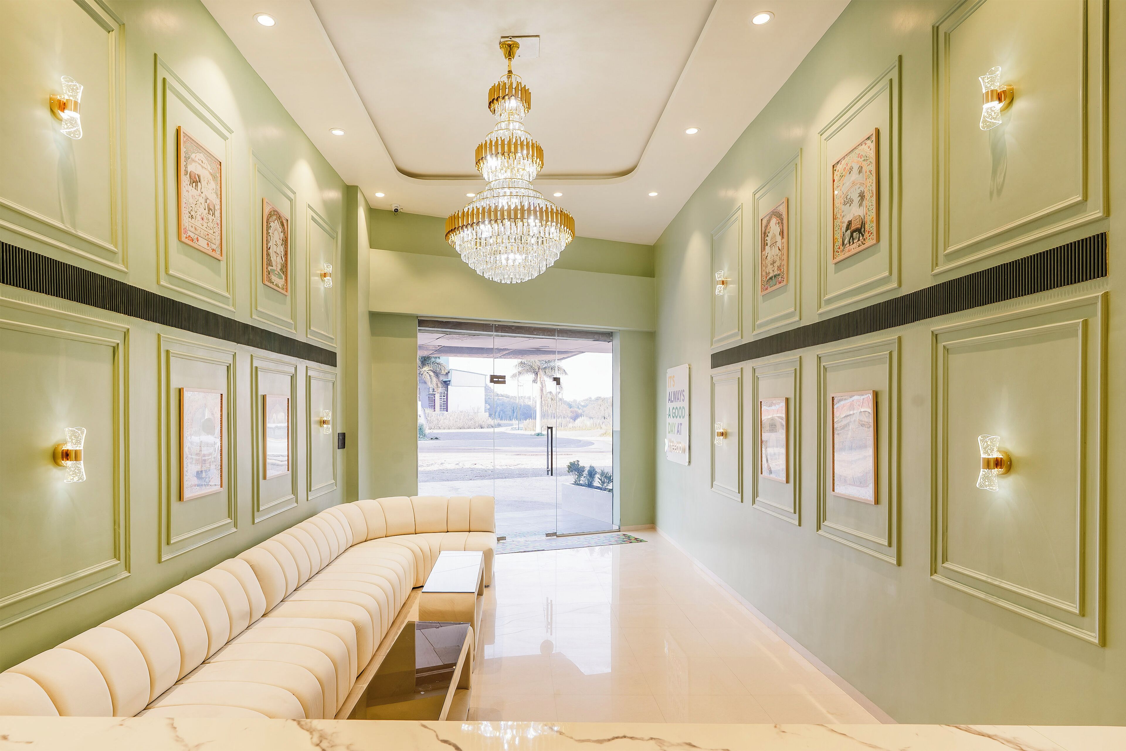 A spacious lobby with a curved white sofa, a marble floor, and framed artwork on the walls.