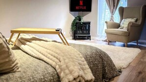 A bedroom with a bed, a TV mounted on the wall, a chair, and a small table. - Cosy cottage with jacuzzi (Cintegabelle)
