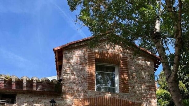 A rustic stone building with a white garage door, a small window, and a tree in the background. - Cosy cottage with jacuzzi (Cintegabelle)