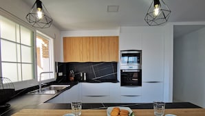 A modern kitchen with a built-in oven, a wooden cabinet, and a black countertop. - LUZ DE LA MARINA - Penthouse in Punta de la Mona of La Herradura (Almuñécar) (Almuñécar)