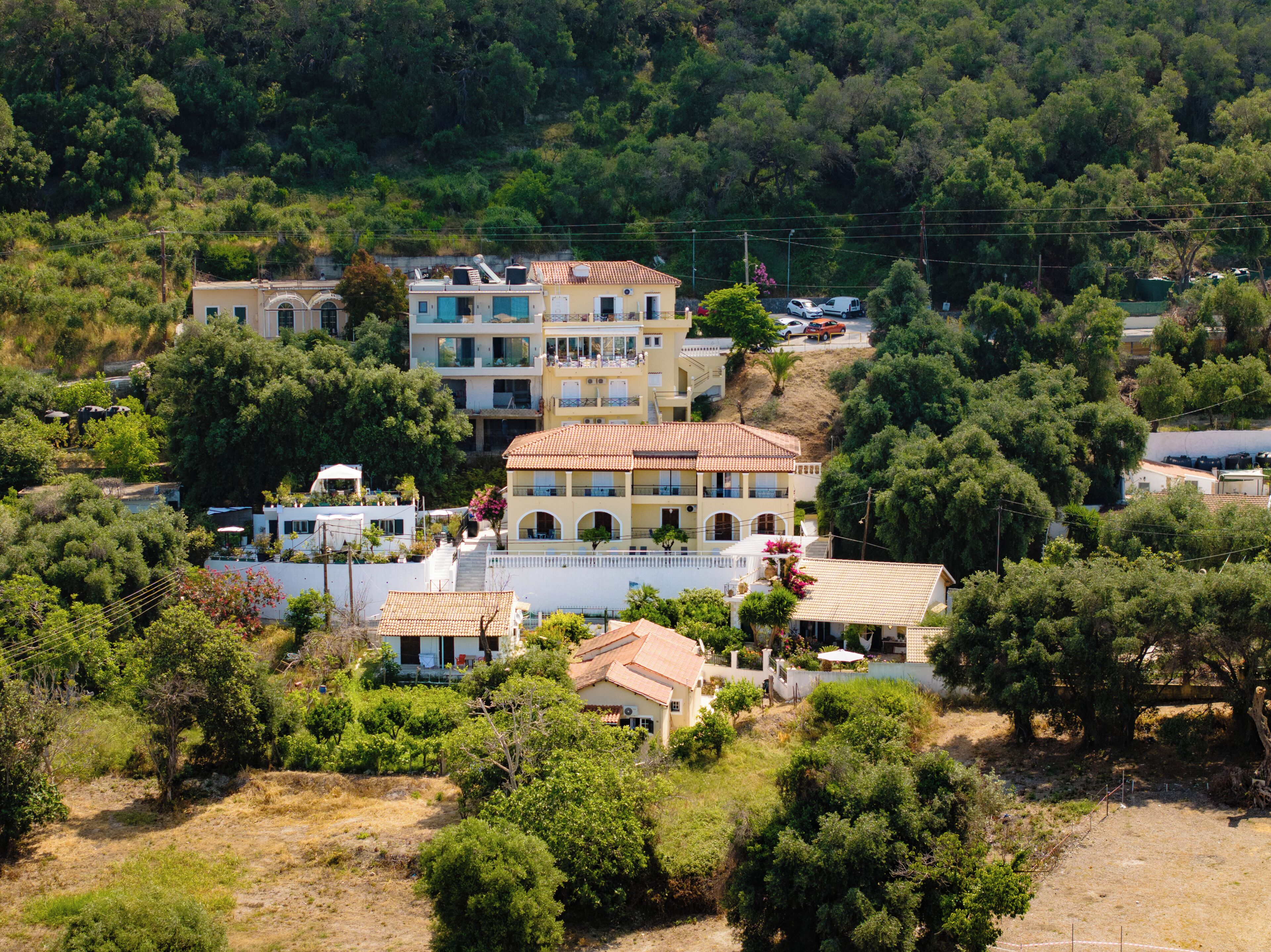 Um edifício com vários andares e varandas, rodeado por vegetação e árvores.