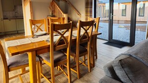 A dining area with wooden furniture, a staircase, and a view of the outside. - Remore Steading - The Coach House (Nairn)