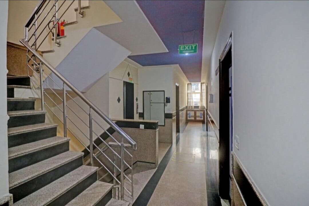 Un pasillo con una escalera, un letrero de salida y un extintor.