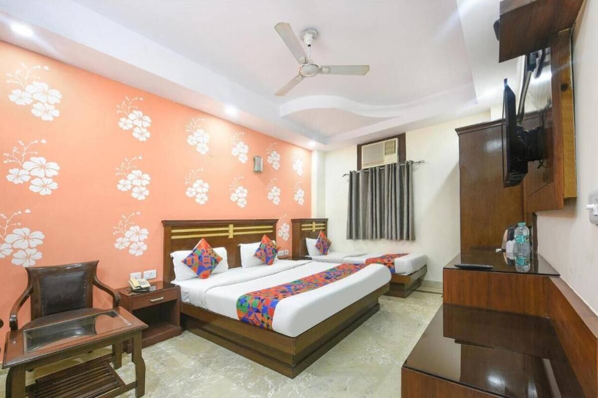 A hotel room with a bed, a desk, a chair, a TV, and a ceiling fan.