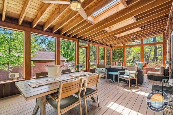 Large screened porch with dining space, lounge seating, and peaceful wooded views for relaxing in every season.