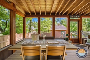 A wooden deck with a table and chairs, a white bucket, and a welcome sign. - 4BR Sleeps 8, Arcade Game Garage, Association Beach Near Lake Como (Lake Geneva)