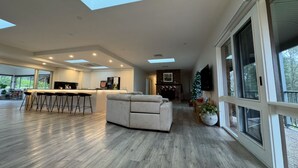 A spacious living area with a sofa, a kitchen with a bar, and large windows.