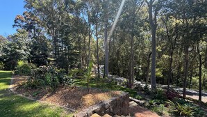 A landscaped garden with a wooden bench, stone pathway, and various plants.