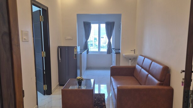 A modern living room with a sofa, coffee table, and a view to the outside. - BHARATHI STAYS (Tirupati)