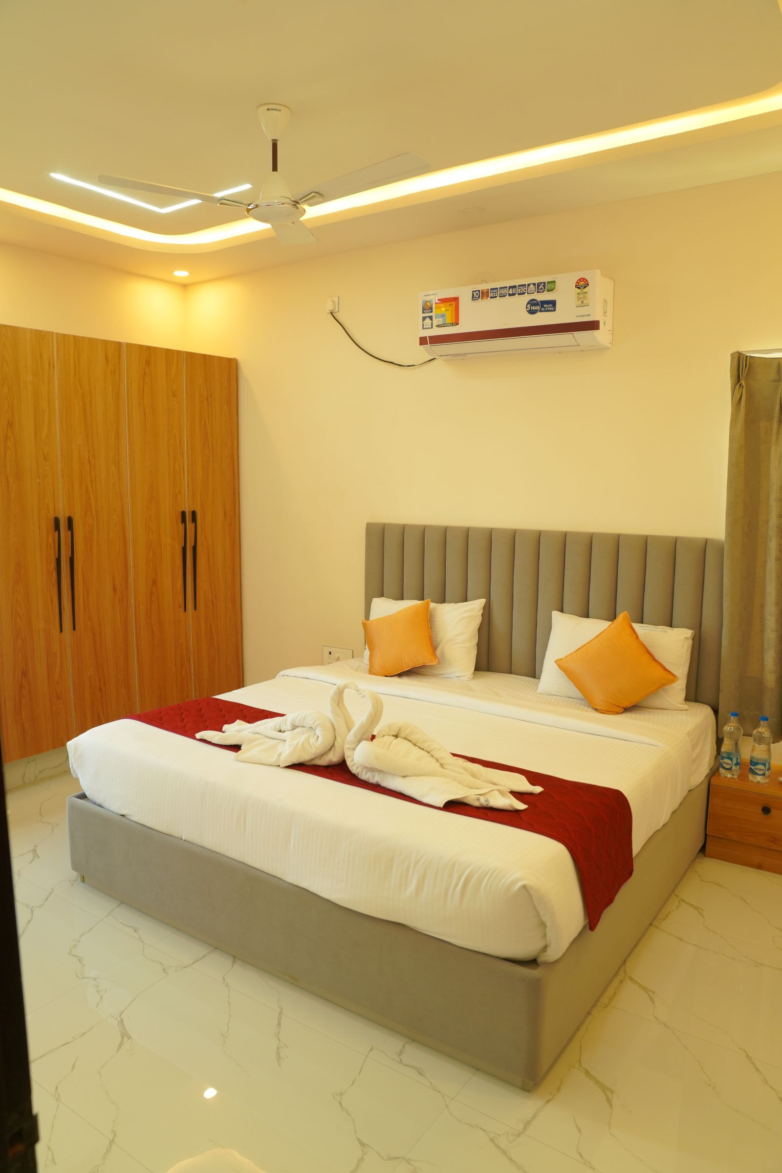 Ein Hotelzimmer mit einem Bett, einem Kleiderschrank, einem Deckenventilator und einer Wandklimaanlage.