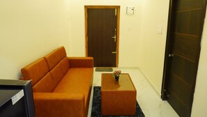 A living room with a sofa, a coffee table, and a door. - BHARATHI STAYS (Tirupati)