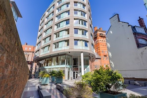 Un hôtel moderne à la façade incurvée, doté de grandes fenêtres et d’une entrée centrale.