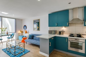 Une cuisine moderne avec des armoires de couleur turquoise, un plan de travail blanc et un four encastré.