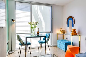 A modern dining area with a glass table, blue chairs, and a bottle of champagne.