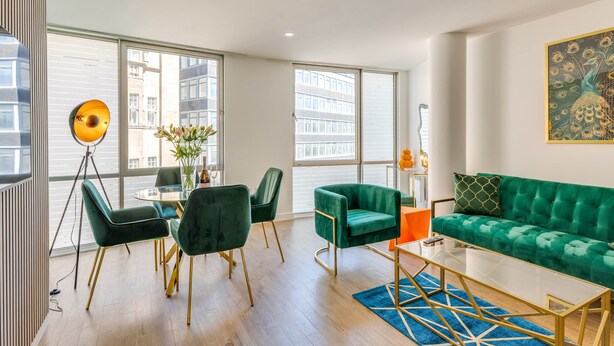 A modern living room with a green sofa, a glass coffee table, and a dining area with chairs and a table. - 404 Hatton Garden Family Flat - Free Secure Parking (Liverpool)