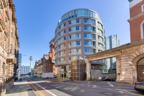 A modern building with a curved facade, a glass elevator, and a clear blue sky. - 404 Hatton Garden Family Flat - Free Secure Parking (Liverpool)
