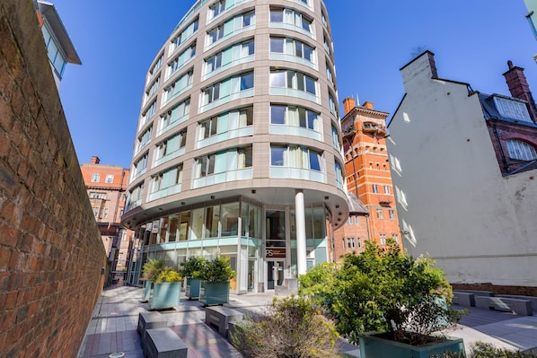 Un hôtel moderne à la façade incurvée, doté de grandes fenêtres et d’une entrée centrale.