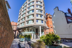 Un hotel modern amb façana corba, finestres grans i una entrada central.