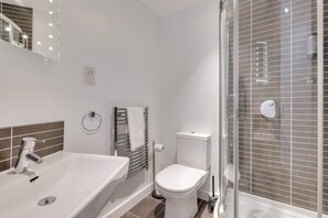 Un bany amb un lavabo, vàter i plat de dutxa blancs.