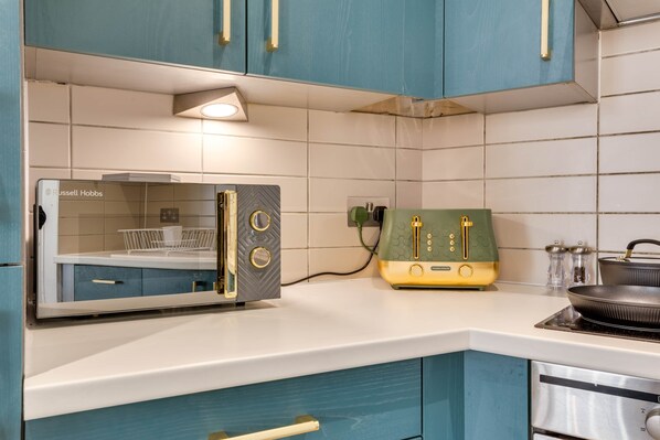 A kitchen with teal cabinets, a microwave, a toaster, and a stove. - 202 Hatton Garden 2-Bed Family Flat with Secure Parking (Liverpool)