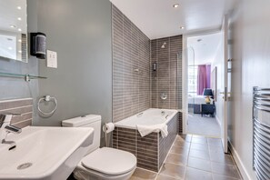 Un baño moderno con una bañera, dos lavamanos y un inodoro.